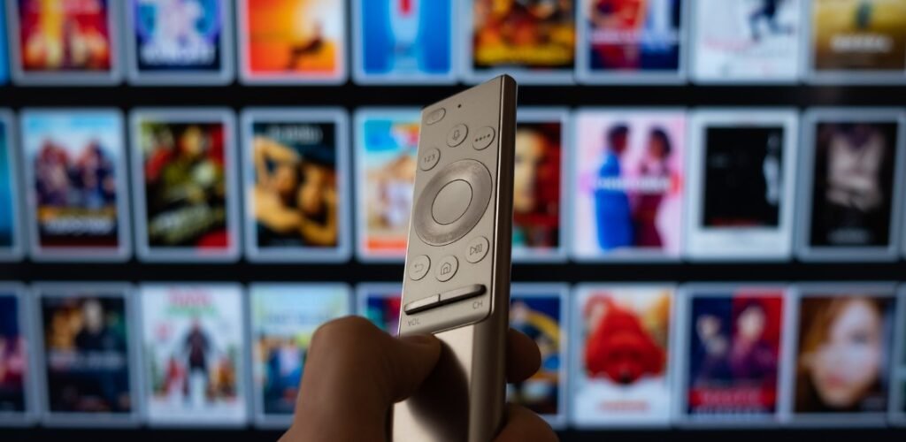 IPTV ULTRA 5 REASONS A hand holding a remote control in front of a smart TV displaying a variety of streaming options, highlighting the benefits of IPTV subscriptions in Canada with IPTV Ultra.